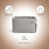 A light gray fabric pet car seat bed shown on a beige gradient background with three informational callouts: a dog icon with 'Gentle car rides for senior pets,' a small square icon with 'Available in Beige and Gray,' and a dog-and-cat icon with 'Great for dogs and cats.'.