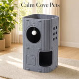 A tall gray felt cat tree with multiple levels, wooden accents, a circular window with a white pom-pom toy, and an open lower compartment, shown in a bright room with the text 'Calm Cove Pets' above it.