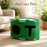 A green felt cat hideaway house with two openings, shown in a bright living room with a sofa, plants, and a window. The text 'Calm Cove Pets' appears at the top.