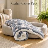 A plush blue pet anxiety blanket featuring cream star patterns in a bright living room The text 'Calm Cove Pets' is visible at the top.