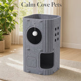 A video of a tall gray felt cat tree with multiple levels, wooden accents, a circular window with a white pom-pom toy, and an open lower compartment, shown in a bright room with the text 'Calm Cove Pets' above it.